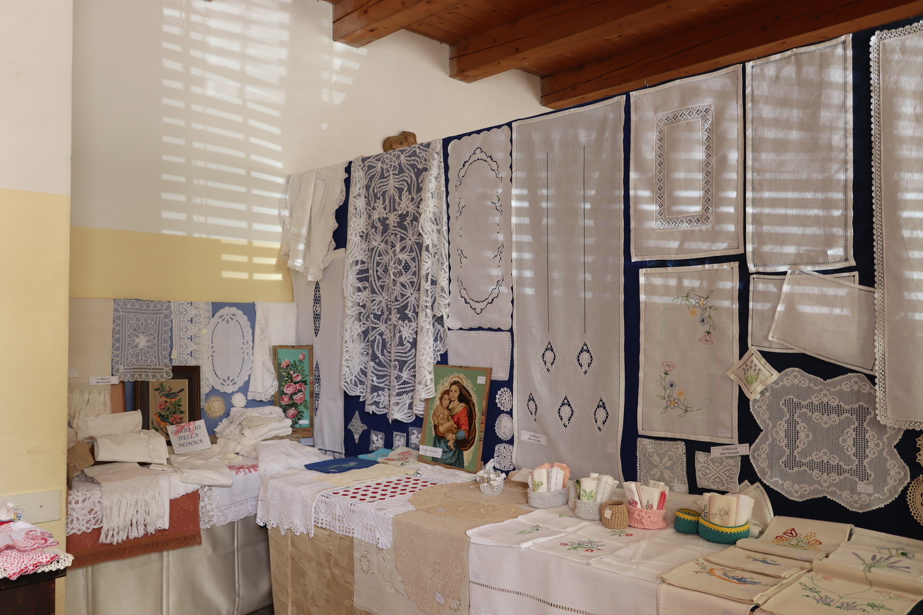 Ricami e tessuti esposti al Mercatino di Manufatti Paesani