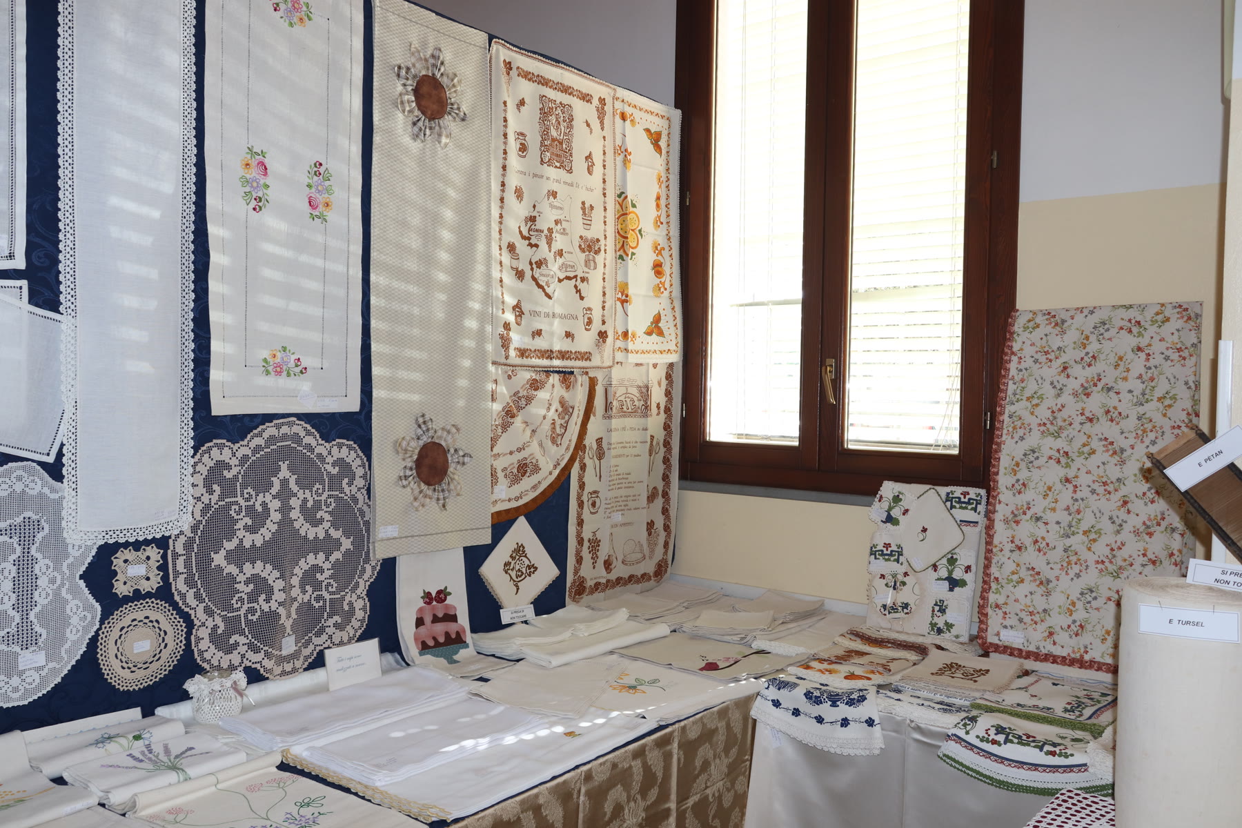 Biancheria e manufatti artigianali esposti al Mercatino di Manufatti Paesani